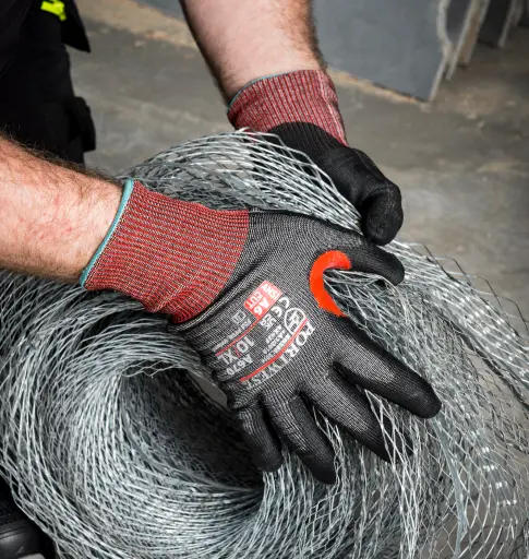Homme tenant une bobine de fer avec des gants de travail